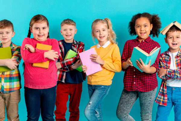 sei bambini uno di fianco all'altro con in mano dei quaderni scolastici