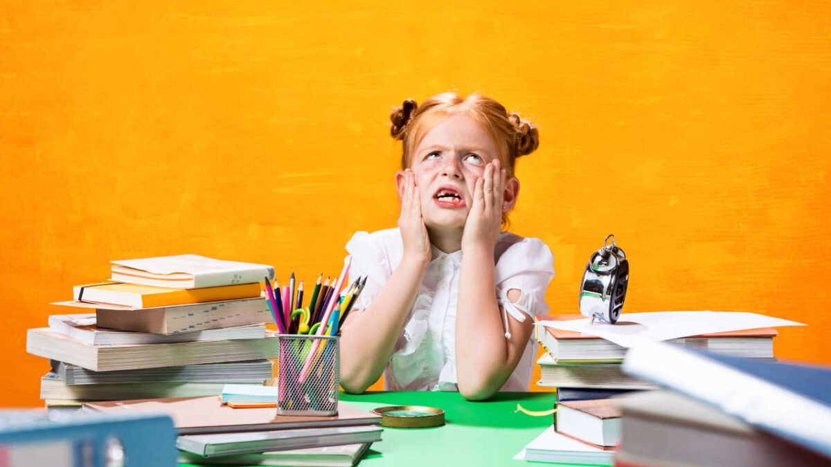 bambina stressata vicino ad una montagna di libri scolastici