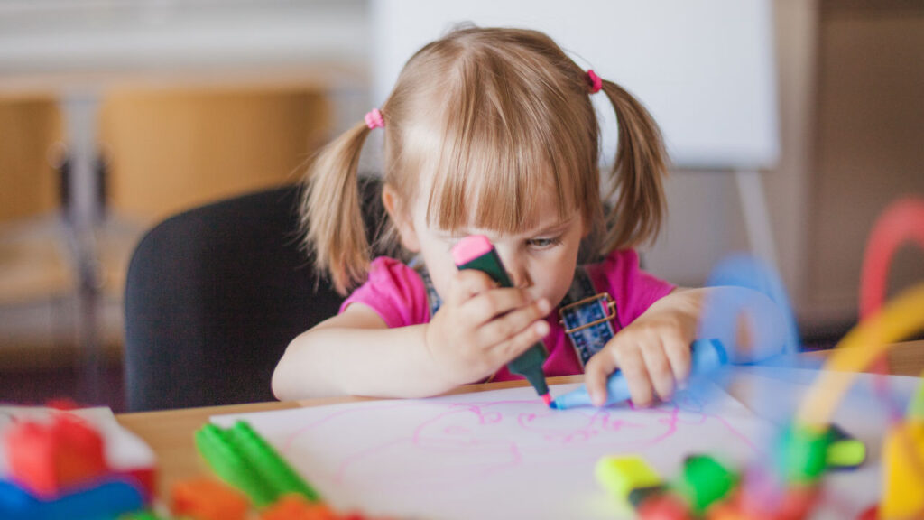 bambina al tavolo che usa un evidenziatore