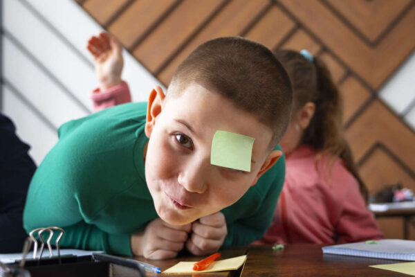 bambino semi disteso su di un bamco con attaccato in fronte un post-it