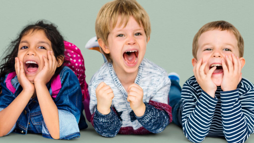 tre bambini distesi dui gomiti che esultano di gioia