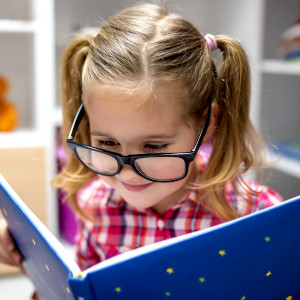 bambina con occhiali chelegge un libro