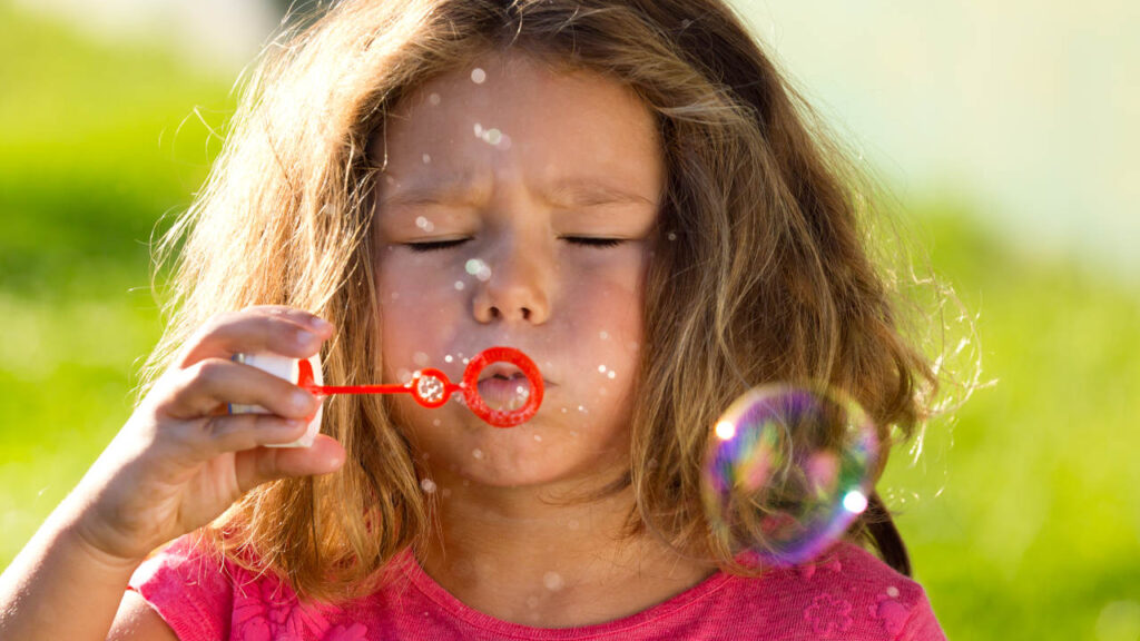 primo piano di bambina che soffia le bolle