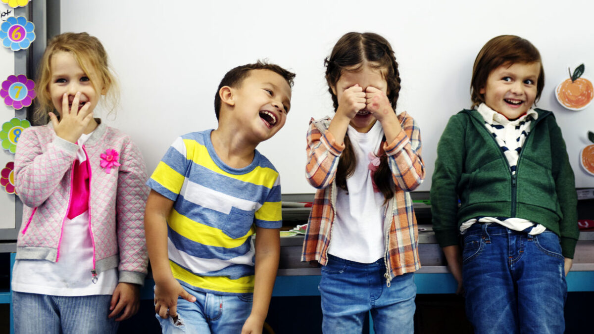 quattro bambini sorridenti davanti ad una lavagna