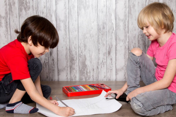 due bambini inginocchio che scrivono su di un pezzo di carta